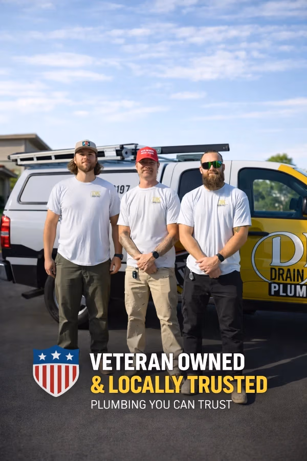 Three plumbers in white shirts stand in front of a service van with the 'Veteran Owned & Locally Trusted' slogan on a sunny day.